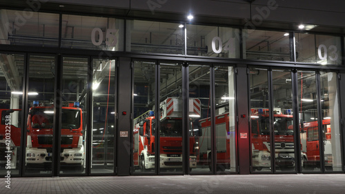 Fire station view at night with fire trucks parked in front of the gates ready to be deployed if necessary. The earliest known firefighting service was formed in Ancient Rome photo