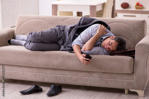 Tired young businessman coming home after working day