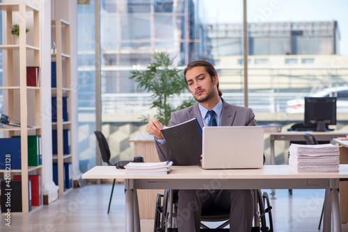 Young male employee in wheel-chair working in the office