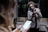 Dead and spooky businessman with zombie greasepaint on face and hands scrolling in smartphone