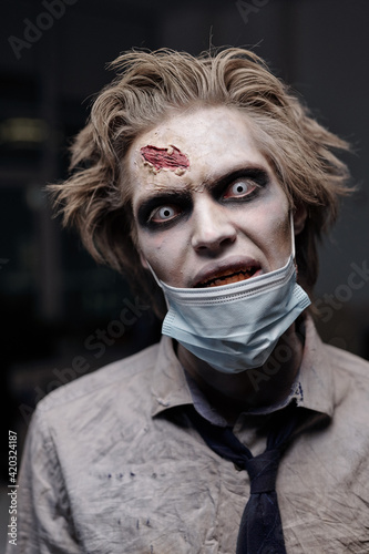 Spooky male zombie with protective mask on chin and crumpled formalwear looking at you sulkily