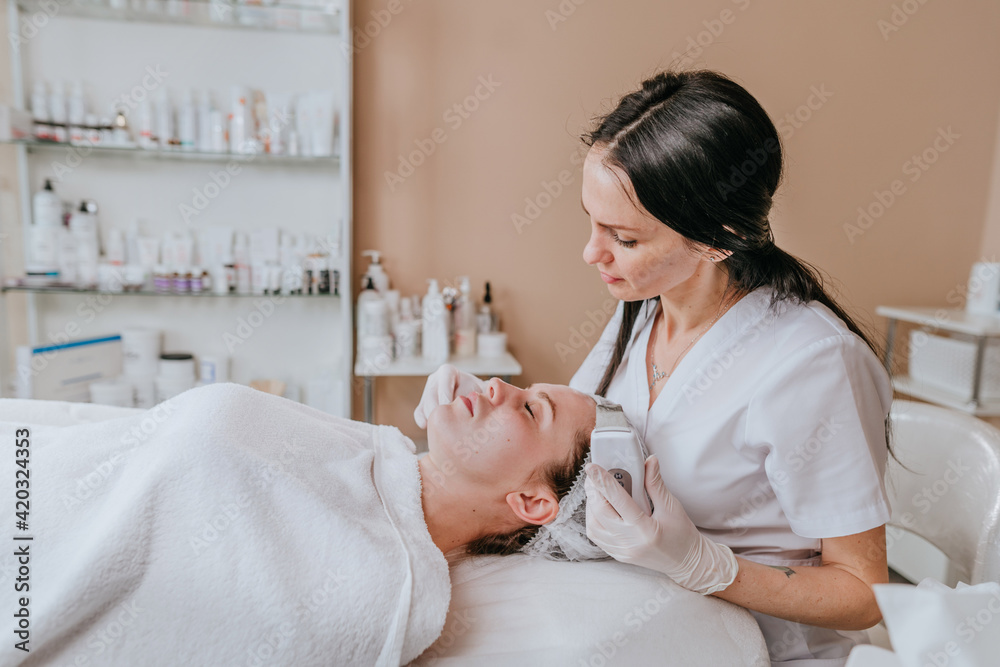 Esthetician making facial cleansing procedure using ultrasonic scin scrubber spatula Esthetician making facial cleansing procedure using ultrasonic scin scrubber spatula