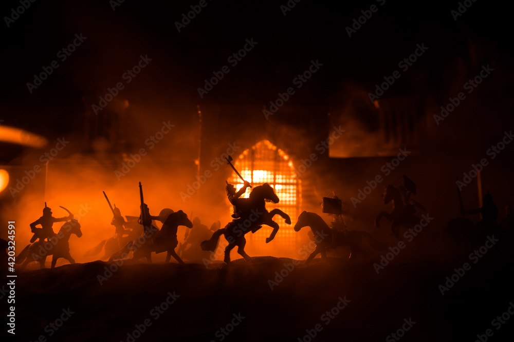 Medieval battle scene with cavalry and infantry. Silhouettes of figures as separate objects, fight between warriors on sunset foggy background.