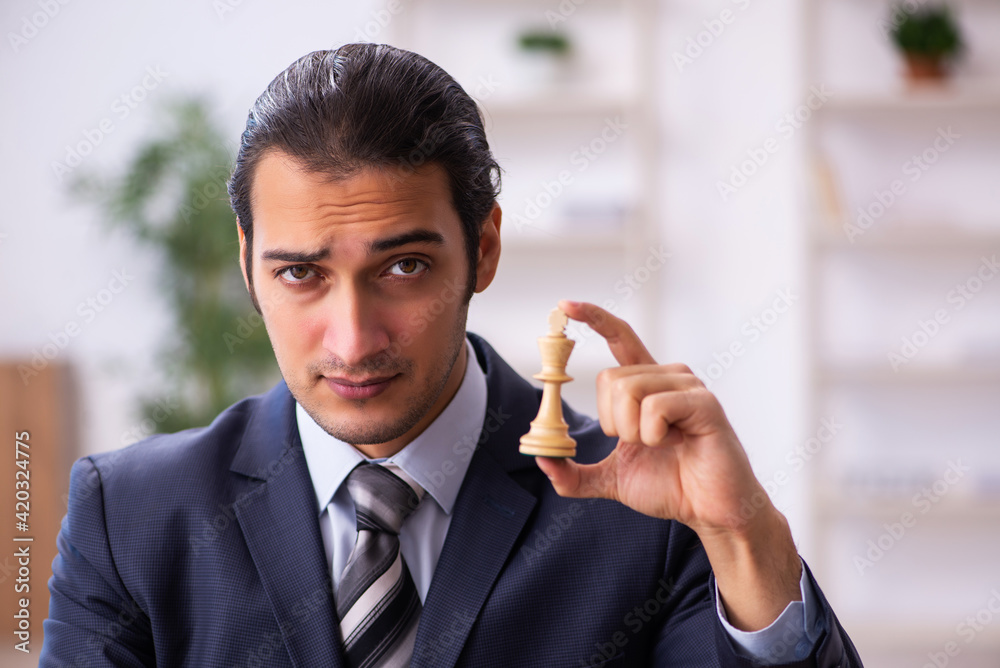 Young male employee playing chess at workplace Young male employee playing chess at workplace