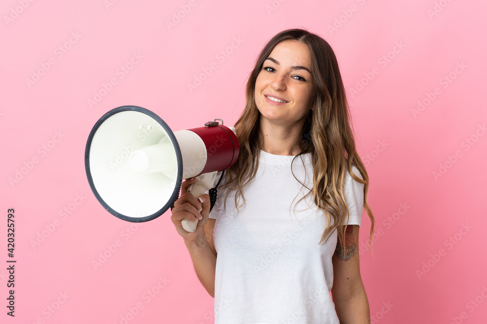 Young Romanian woman isolated on pink background holding a megaphone and smiling a lot Young Romanian woman isolated on pink background holding a megaphone and smiling a lot