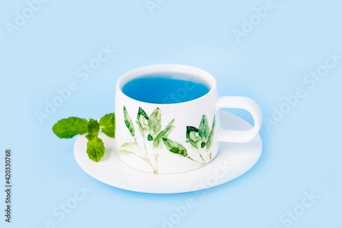 Porcelain cup of organic blue butterfly pea flower tea with mint leaf