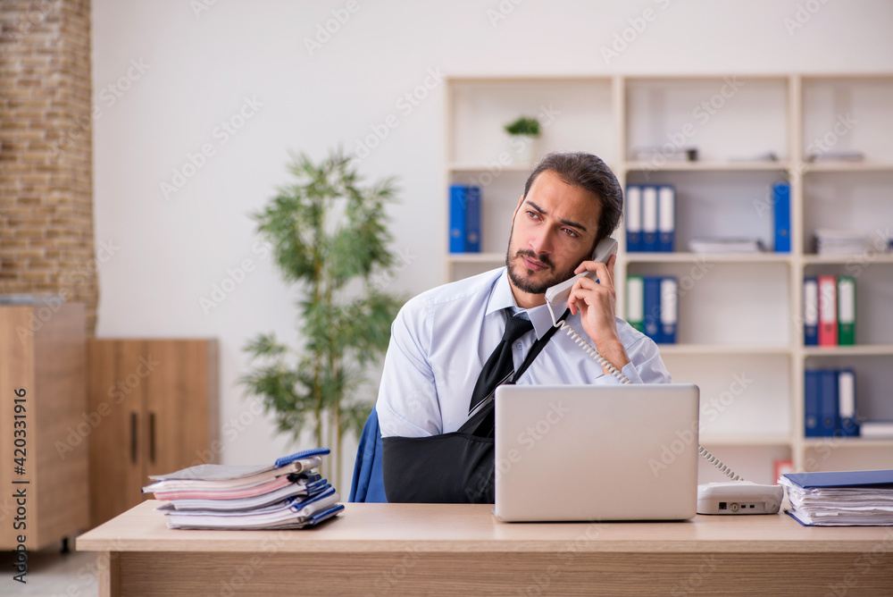 Fototapeta premium Young arm injured male employee working in the office