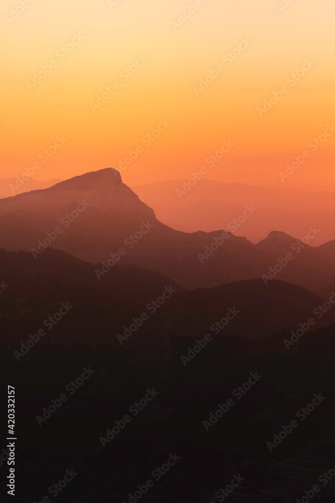 Stunning misty sunset over mountain silhouette horizon