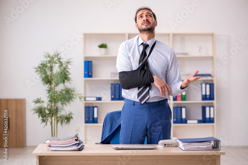 Young arm injured male employee working in the office