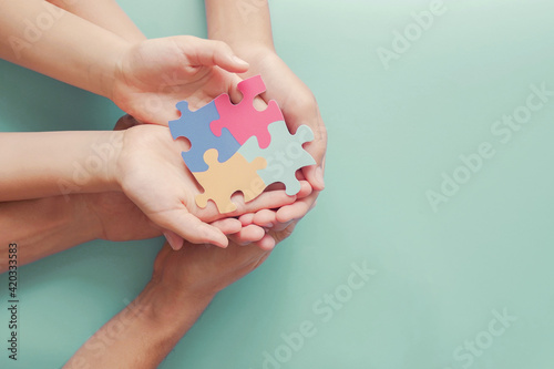 Adult and chiildren hands holding jigsaw puzzle shape, Autism awareness,Autism spectrum disorder family support concept, World Autism Awareness Day