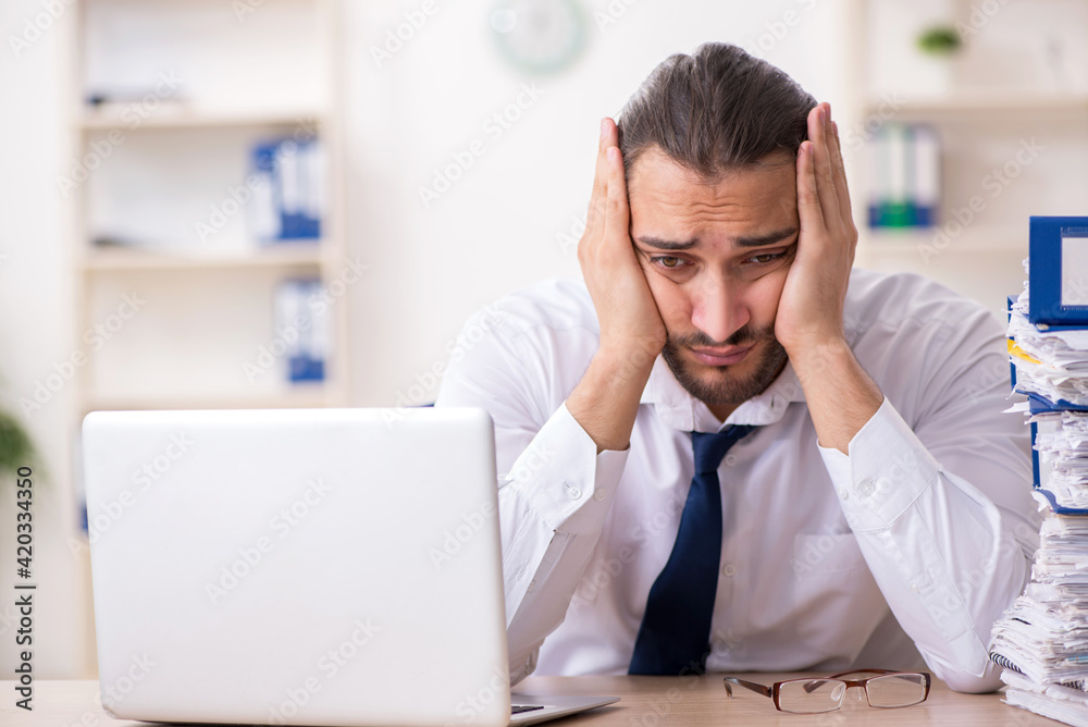 Young businessman unhappy with excessive work in the office Young businessman unhappy with excessive work in the office
