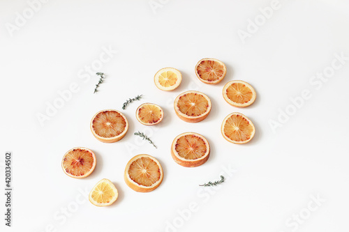 Composition of fresh whole and slice cut bloody oranges with thyme herb isolated on white table backgrounds. Fruit pattern. Food concept. Summer decoration, web banner. Flat lay, top view.