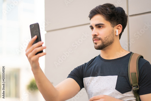 Canvas Print Young man using face id for unlock mobile phone outdoors.