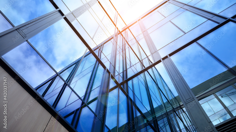 Modern office building with glass facade on a clear sky background. Transparent glass wall of office building. Modern office building with glass facade on a clear sky background. Transparent glass wall of office building.