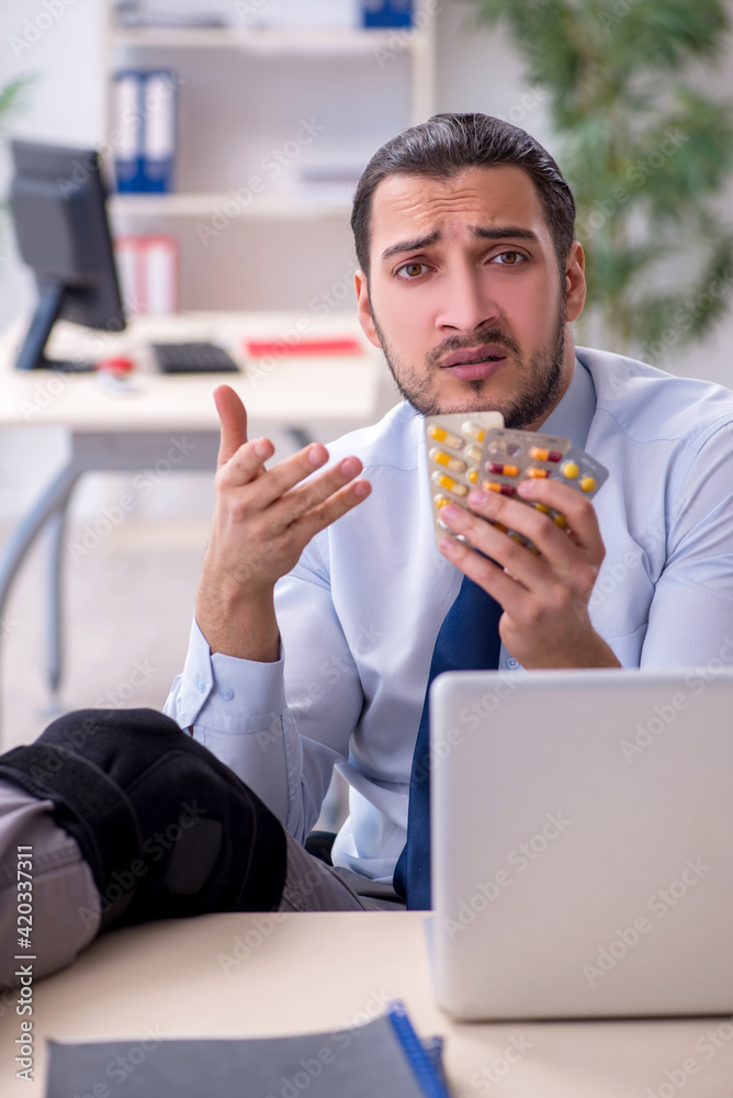 Young leg injured employee working in the office Young leg injured employee working in the office