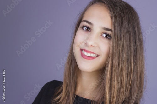 Portrait of a young brunette girl isolated on purple background