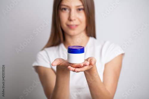 Beautiful young woman holding moisturizer cream on her hands