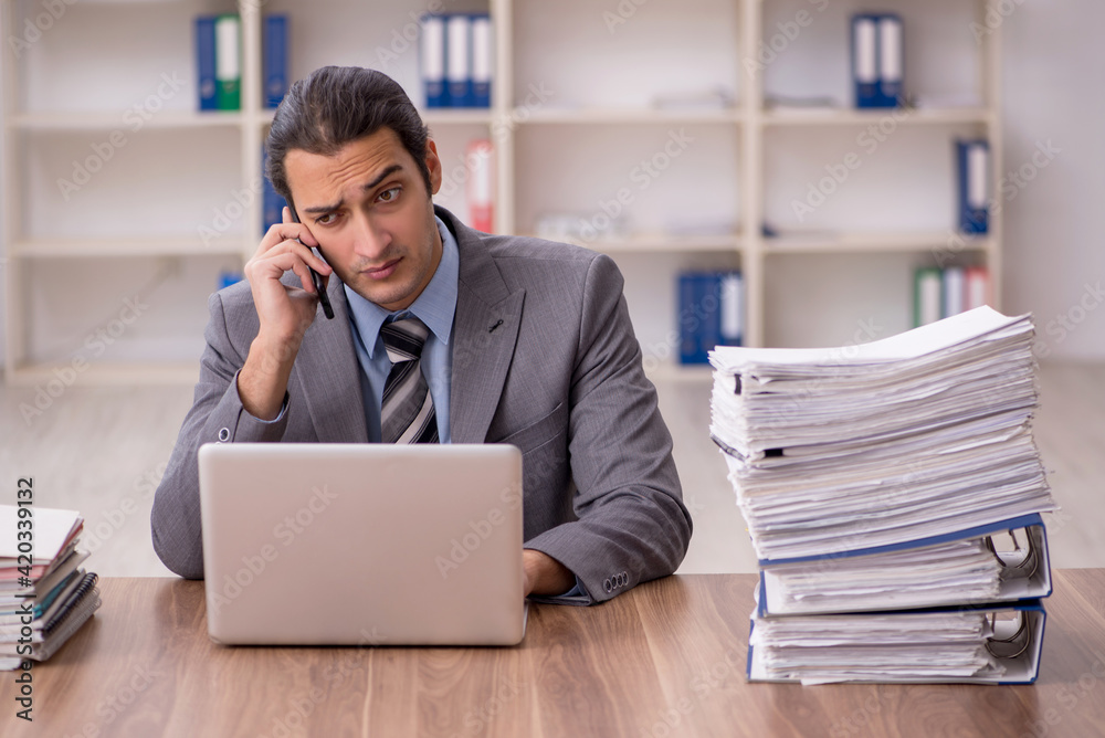 Young male employee unhappy with excessive work in the office Young male employee unhappy with excessive work in the office