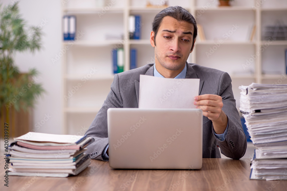 Young male employee unhappy with excessive work in the office