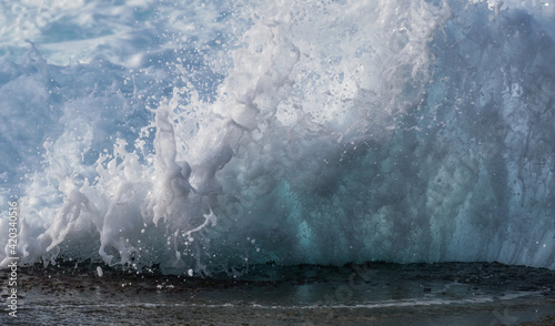 Fototapeta Naklejka Na Ścianę i Meble -  wave breaking on the rocks with bubbles and white foam 