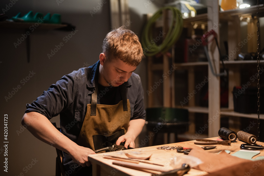 a young shoemaker in a Shoe shop makes shoes from leather with his own hands a young shoemaker in a Shoe shop makes shoes from leather with his own hands