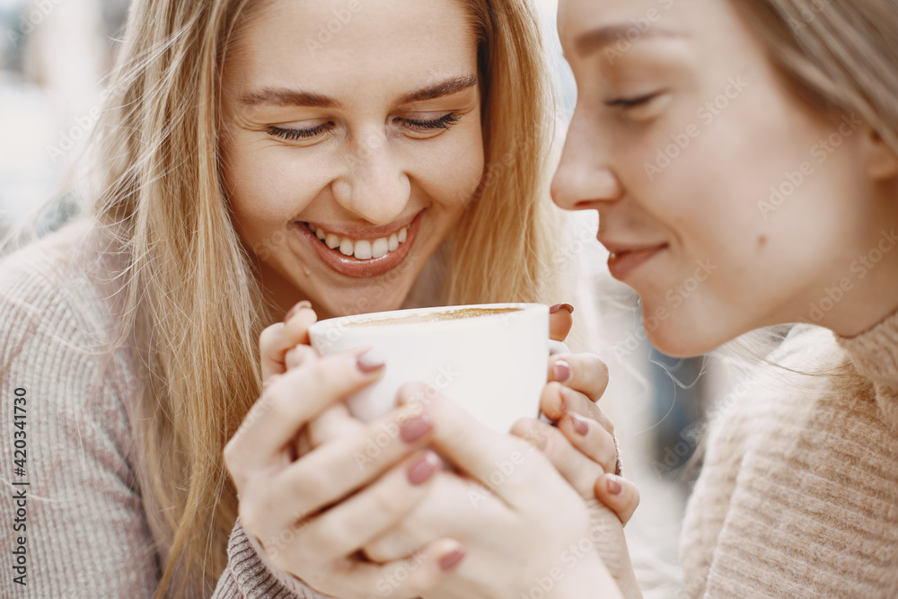 Girls in light clothes. Winter coffee on balcony. Happy women together. Girls in light clothes. Winter coffee on balcony. Happy women together.