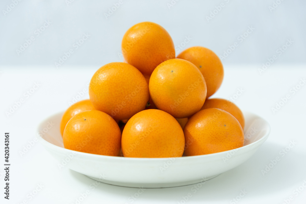 A saucer of kumquat isolated on white background, seasonal fruit A saucer of kumquat isolated on white background, seasonal fruit