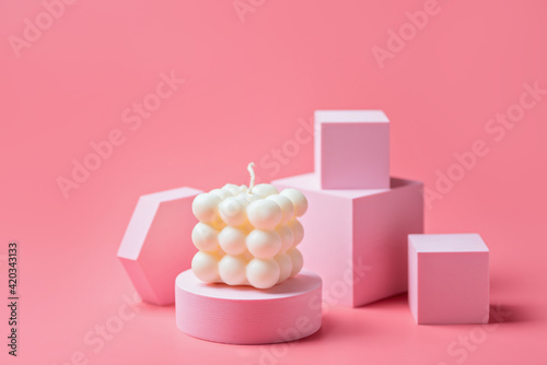 A trendy soy cube bubble candle on a pink podium at the pink background