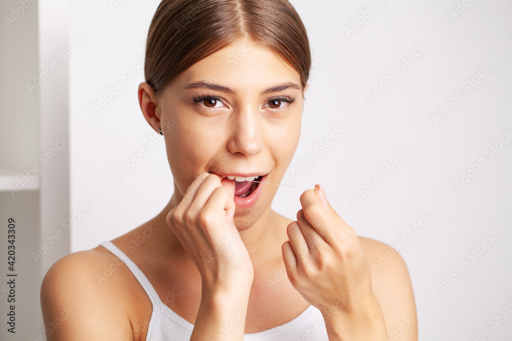Cheerful brunette woman using dental floss in bathroom Cheerful brunette woman using dental floss in bathroom