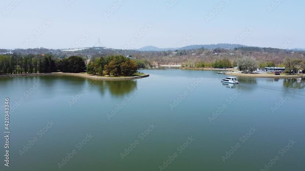 Flying towards Canberra's Parliament House as a tourist boat cruises on the lake. Flying towards Canberra's Parliament House as a tourist boat cruises on the lake.