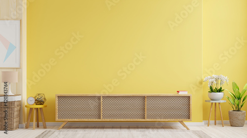 Cabinet TV in modern living room with lamp,table,flower and plant on yellow wall background.