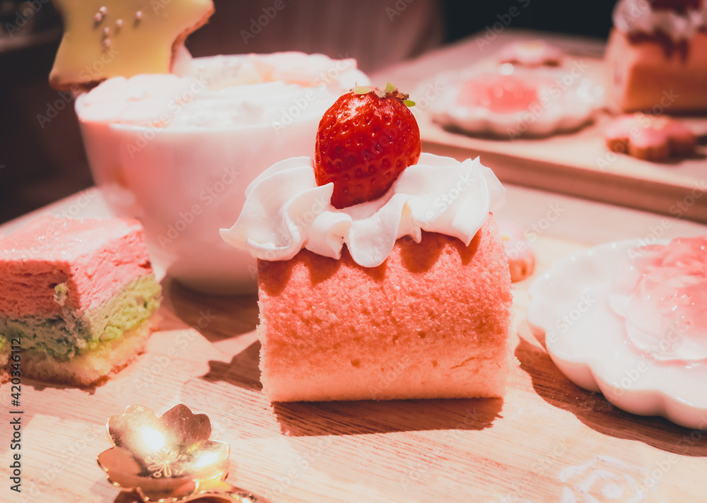 Sakura Roll Cake with a strawberry on top on a cake plate with a cup in the background Sakura Roll Cake with a strawberry on top on a cake plate with a cup in the background
