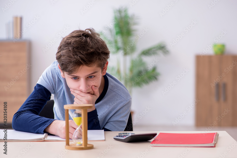 Schoolboy preparing for exams in time management concept Schoolboy preparing for exams in time management concept