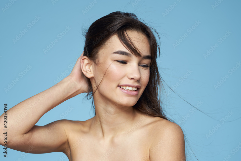 Woman with naked shoulders long hair cosmetics attractive look blue background Woman with naked shoulders long hair cosmetics attractive look blue background