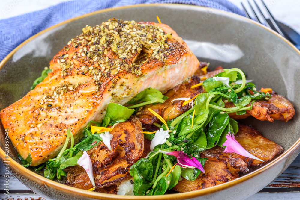 Grilled salmon served with crispy chat potatoes, snow pea tendrils and dukkah butter Grilled salmon served with crispy chat potatoes, snow pea tendrils and dukkah butter
