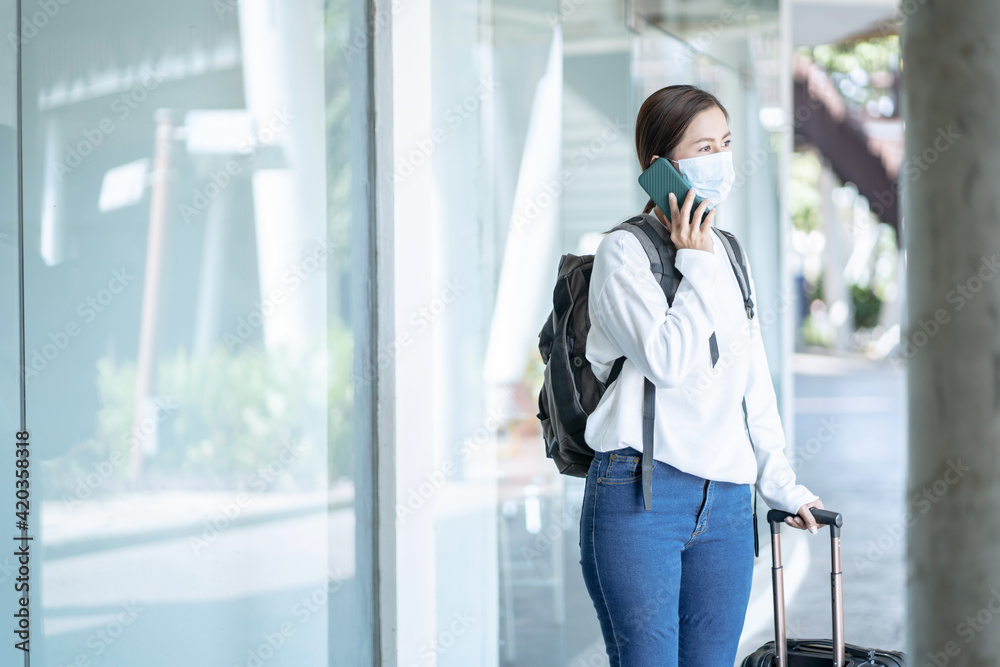 Asian woman passenger wearing face mask using mobile phone at transport station, new normal, corona virus, covid-19.. Asian woman passenger wearing face mask using mobile phone at transport station, new normal, corona virus, covid-19..