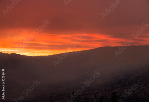 red fiery sky and dark clouds cover the summer Yosemite sky due to a forest fire.