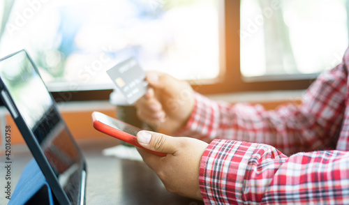 Man's hands holding a credit card and using smart phone for online shopping. Credit card for pay and shopping online. Online payment concept. Freelancer in coffee shop and working.