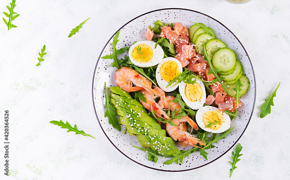 Ketogenic diet breakfast. Salt salmon salad with boiled shrimps, prawns, cucumbers, arugula, eggs and avocado. Keto, paleo lunch. Top view, overhead Ketogenic diet breakfast. Salt salmon salad with boiled shrimps, prawns, cucumbers, arugula, eggs and avocado. Keto, paleo lunch. Top view, overhead