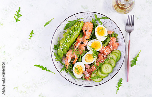 Ketogenic diet breakfast. Salt salmon salad with boiled shrimps, prawns, cucumbers, arugula, eggs and avocado. Keto, paleo lunch. Top view, overhead