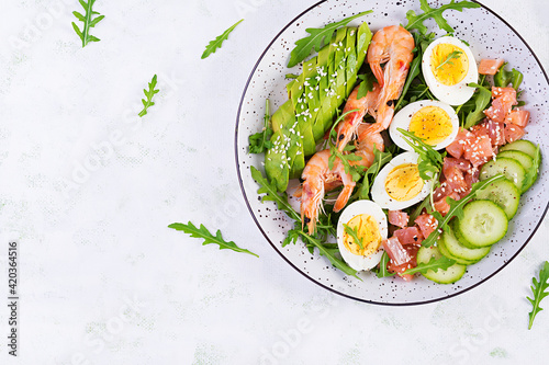 Ketogenic diet breakfast. Salt salmon salad with boiled shrimps, prawns, cucumbers, arugula, eggs and avocado. Keto, paleo lunch. Top view, overhead