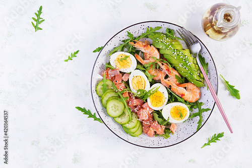 Ketogenic diet breakfast. Salt salmon salad with boiled shrimps, prawns, cucumbers, arugula, eggs and avocado. Keto, paleo lunch. Top view, overhead