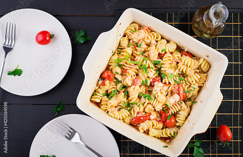 Fetapasta. Trending Feta bake pasta recipe made of cherry tomatoes, feta cheese, garlic and herbs. Table setting.  Top view, above, copy space. photo