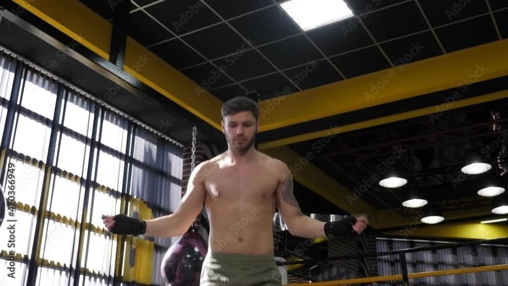A handsome male boxer jumps on a skipping rope in a boxing gym. A handsome male boxer jumps on a skipping rope in a boxing gym.