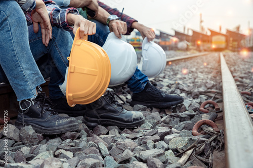 A group of workers holding hard hat and engineers rested on the tracks after their hard work. Teamwork engineer work together in a construction railway. 