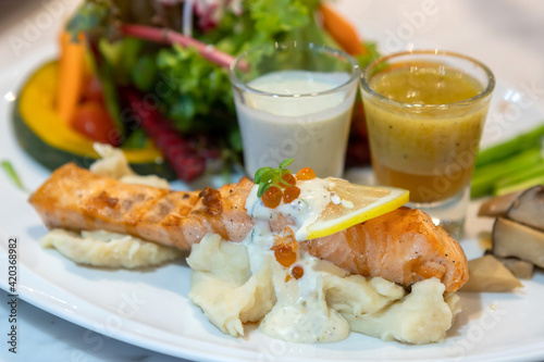 grilled salmon steak , lime on top with salad and potatoes mashed on white tartar sauce