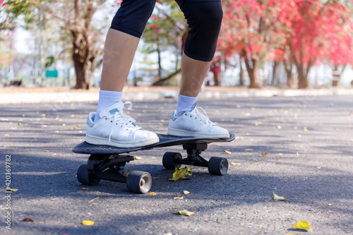 Close-up Asian women surf skate or skateboard outdoors on beautiful morning. Happy young women play surf skate at ramp park on morning time. Close up Asian women leg wear sneaker play surf skate  © AKGK Studio