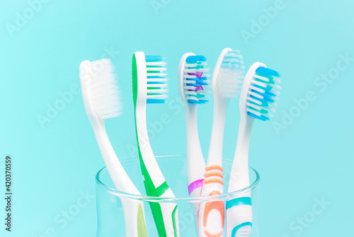 Toothbrushes in glass cup on blue background close-up.