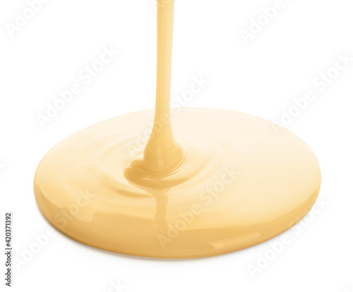 Pouring of condensed milk on white background