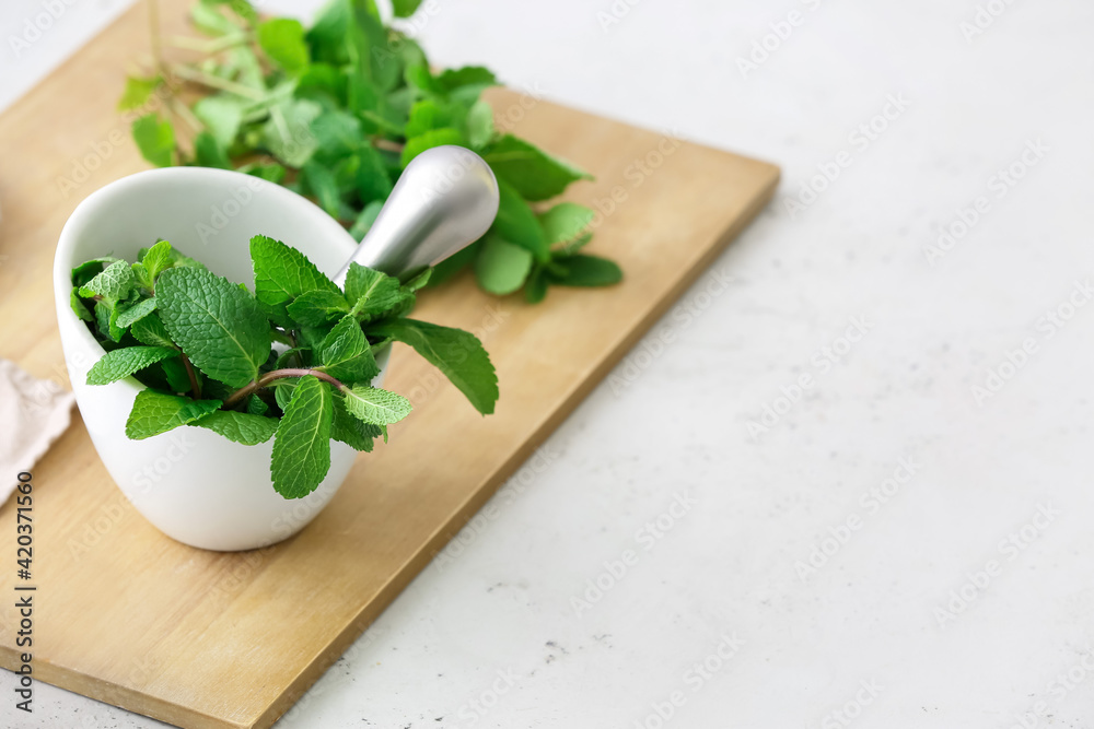 Mortar with mint and pestle on light table in kitchen Mortar with mint and pestle on light table in kitchen